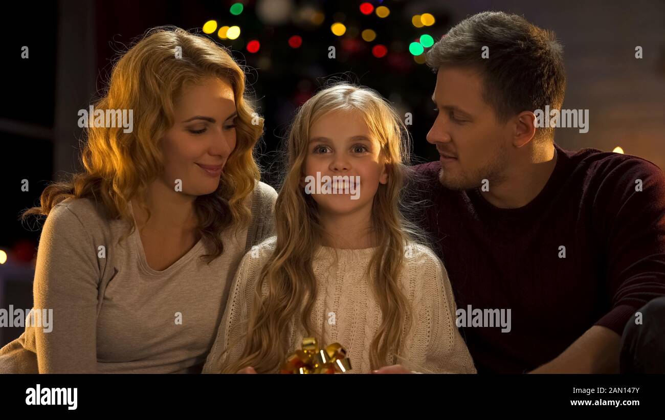 Excited girl holding gift from parents, childish dreams come true at Christmas Stock Photo