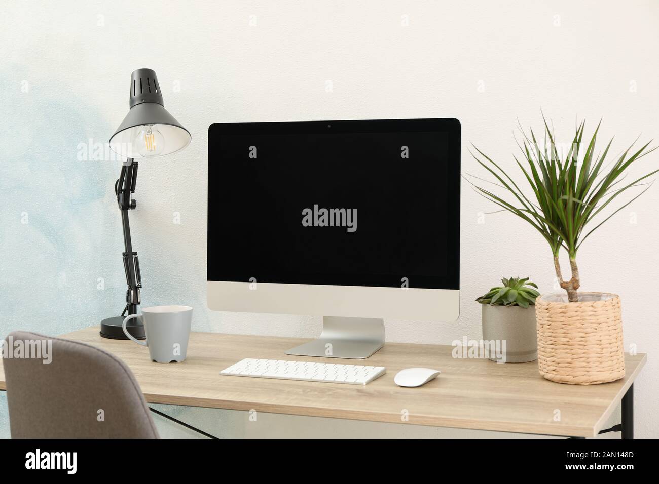 Workplace with computer, plants and lamp on wooden table. Empty black screen Stock Photo
