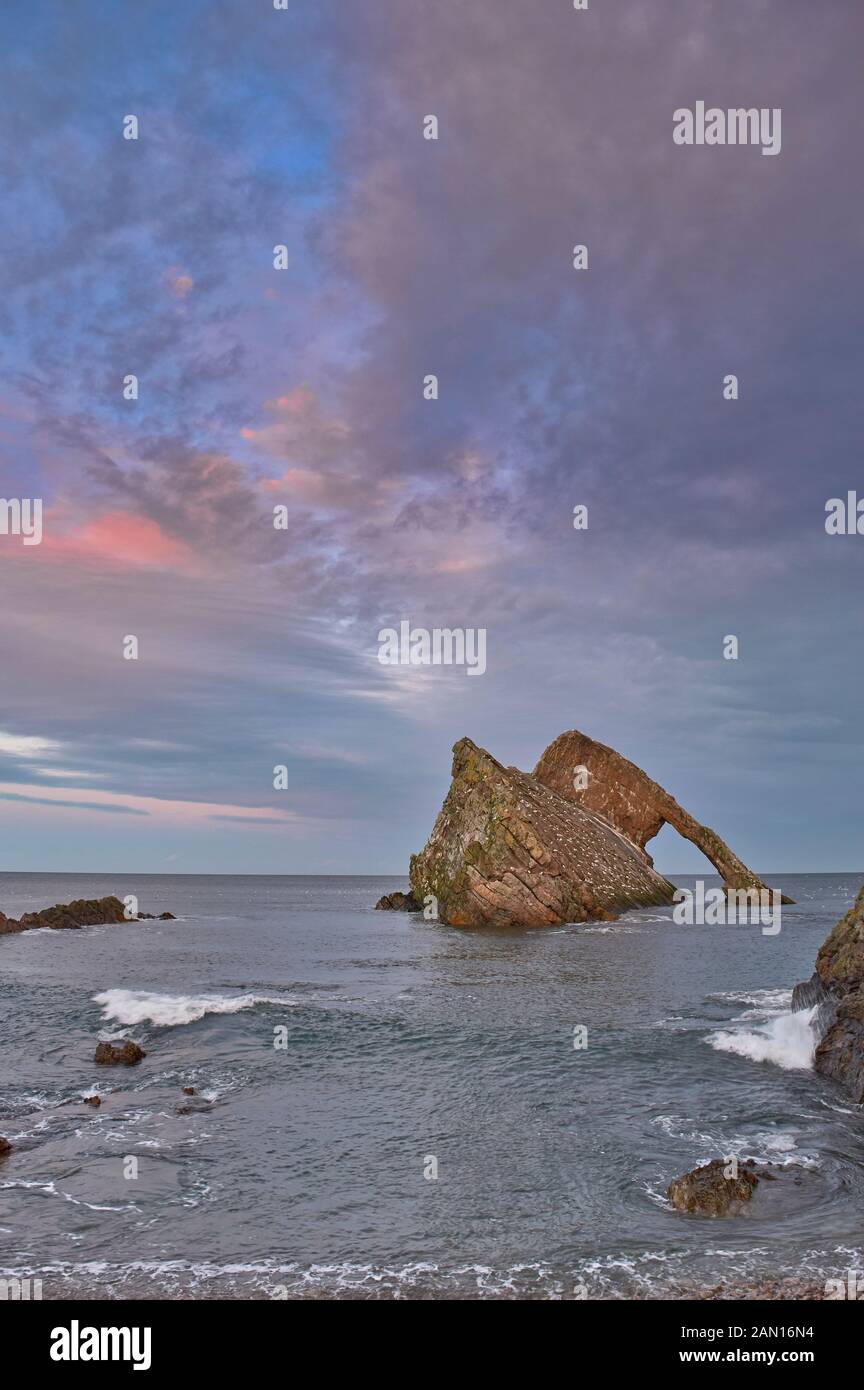 BOW FIDDLE ROCK PORTKNOCKIE MORAY SCOTLAND JANUARY A PINK CLOUD SUNSET IN WINTER A CALM SEA AND HIGH TIDE Stock Photo