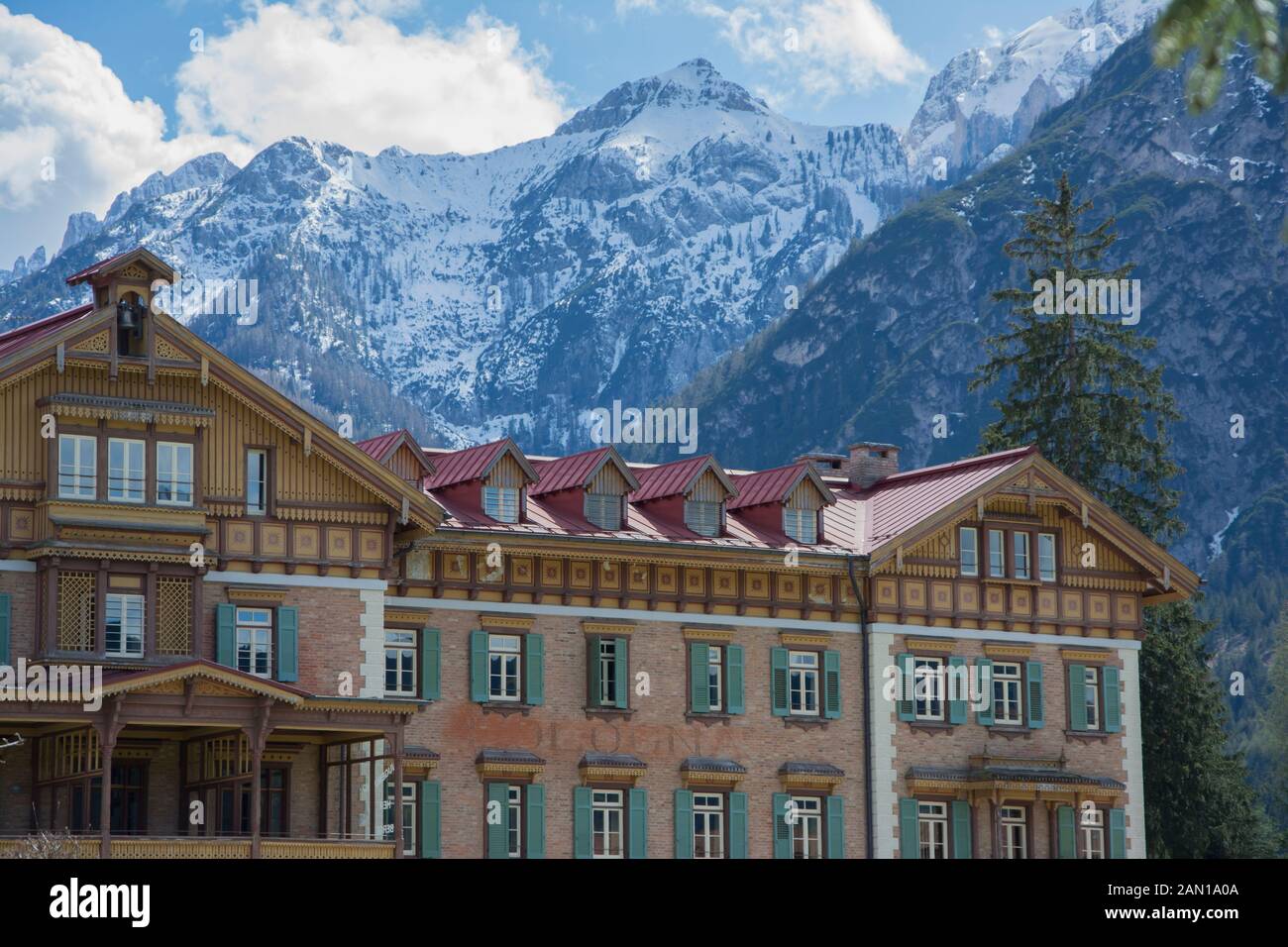 View of the Grand Hotel Toblach with mountains and trees in the background Stock Photo