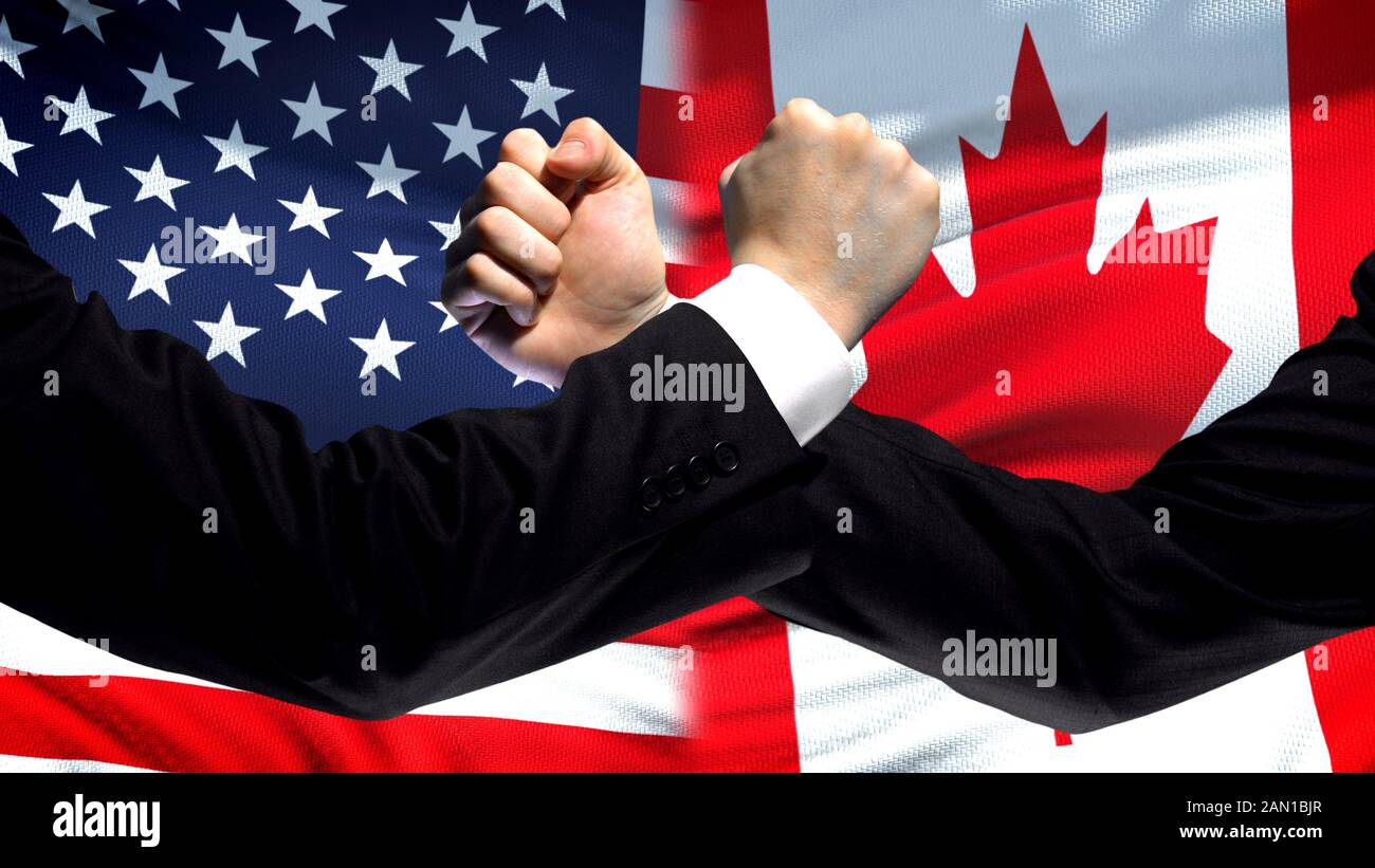 US vs Canada confrontation, countries disagreement, fists on flag background Stock Photo