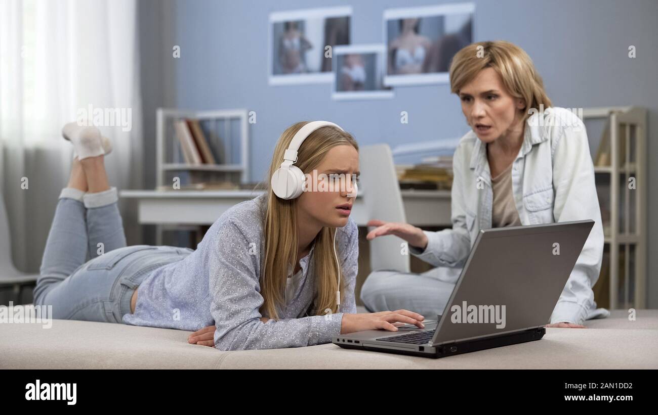 Teenage son listening music in headphones or playing online games ignoring  his mother Stock Photo - Alamy