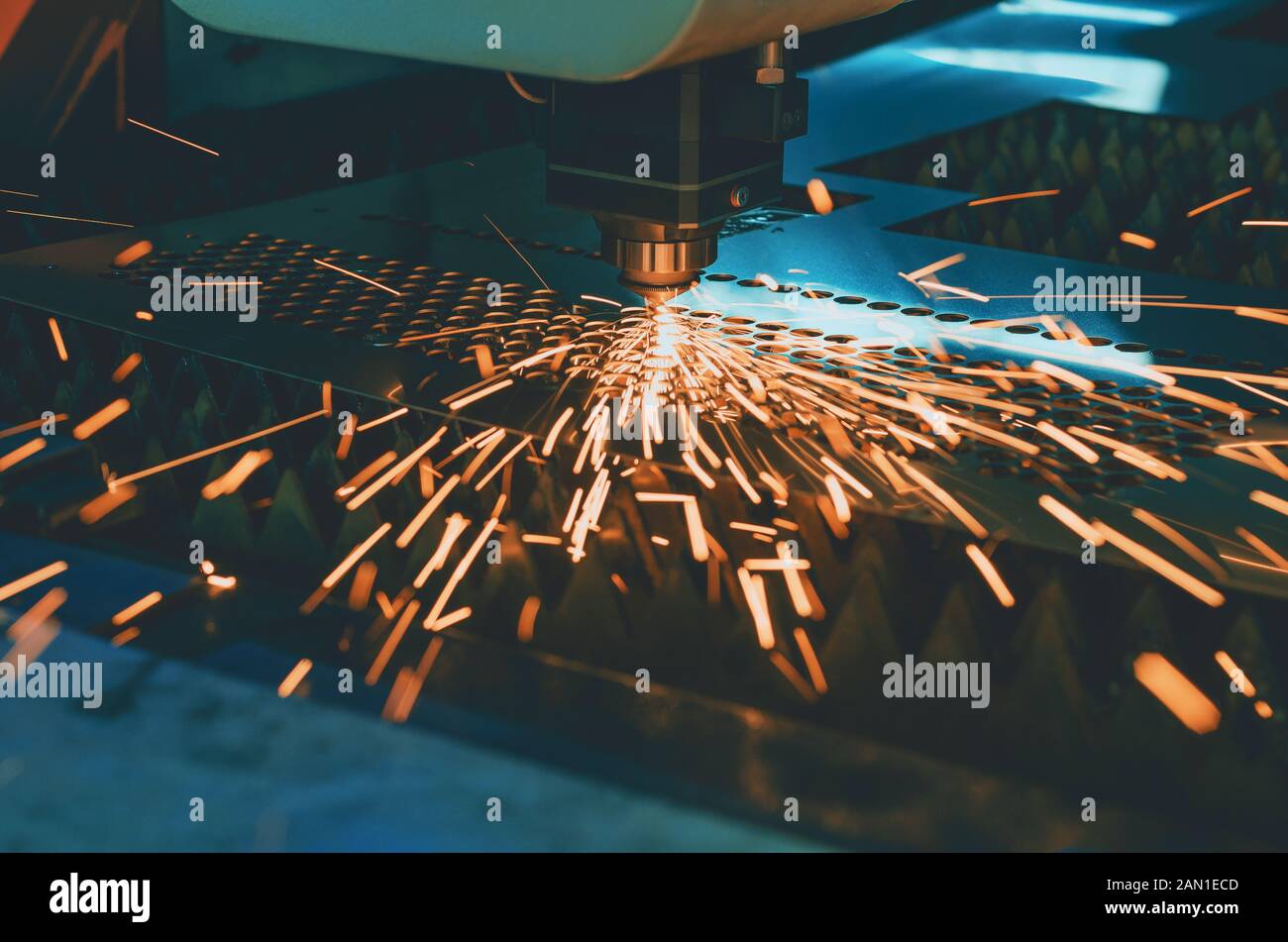 Machine for laser cutting of metal. Laser head cuts the sheet with a beam, sparks scatter in different directions Stock Photo