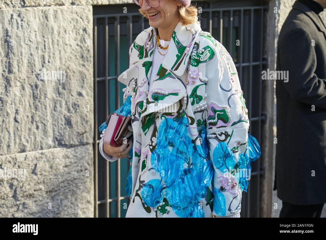 MILAN, ITALY - JANUARY 11, 2019: Woman with white jacket with floral design and blue transparent details before Emporio Armani fashion show, Milan Fas Stock Photo