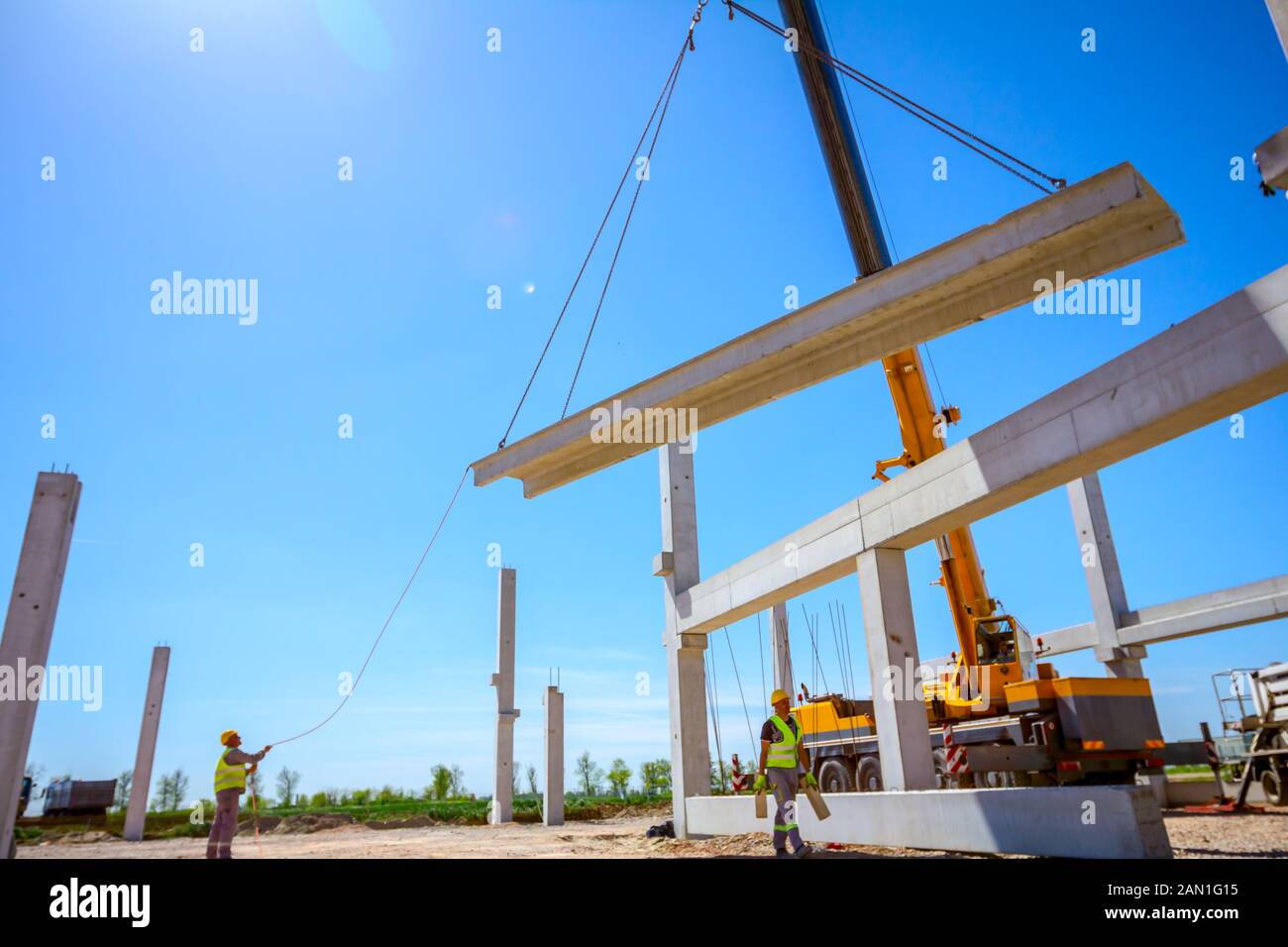 Worker is helping mobile crane with rope to manage concrete joist for ...