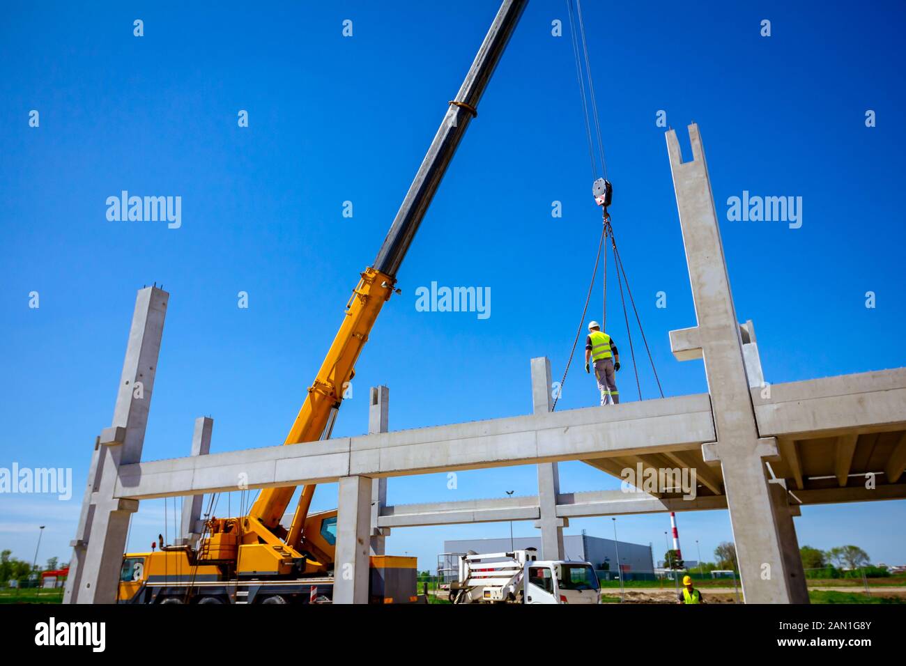 Worker is helping mobile crane to manage concrete joist for assembly ...