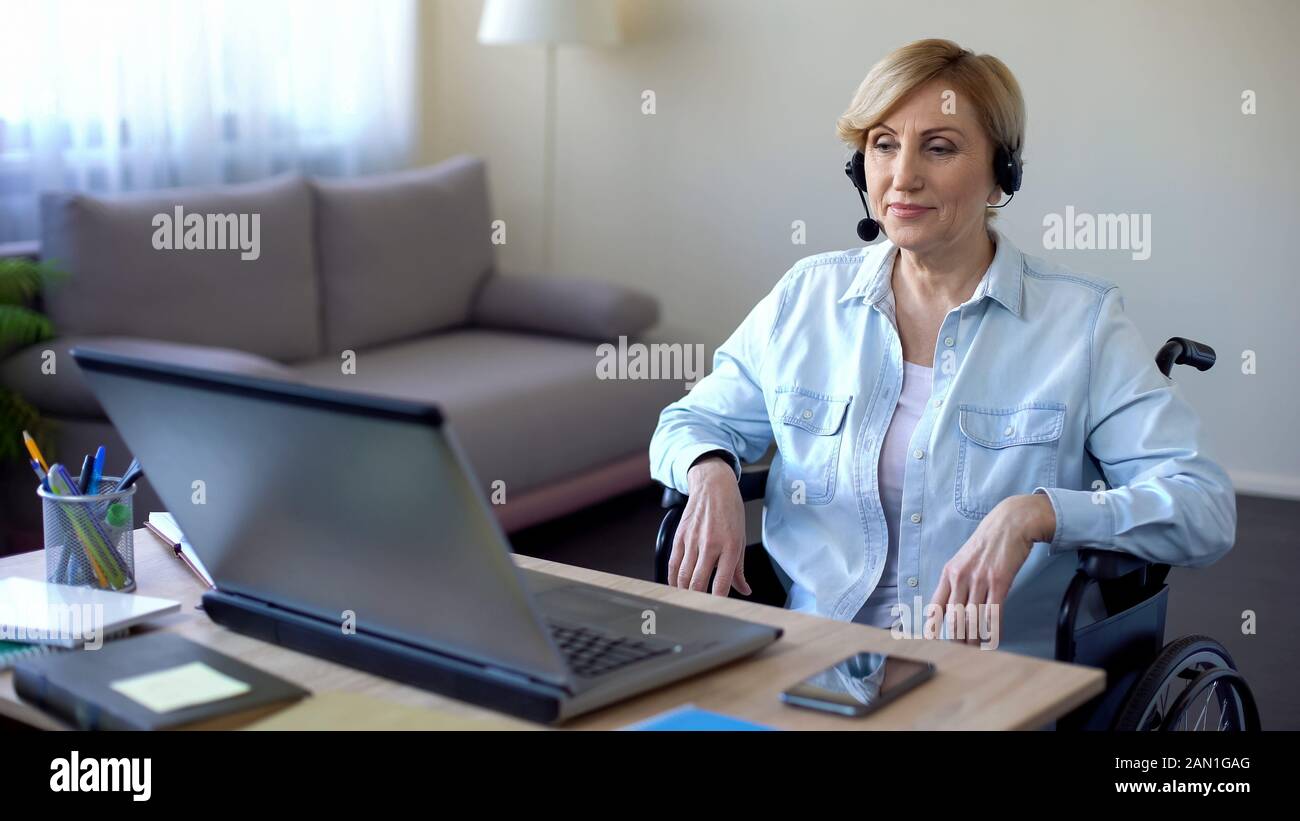 Call-center female operator in headphones talking with client, disabled woman Stock Photo