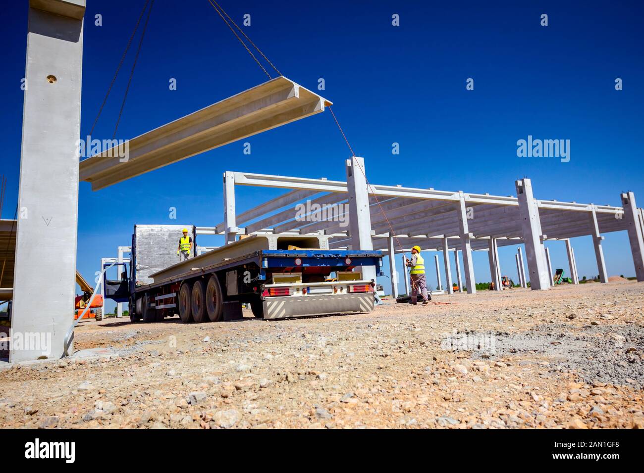 Trailer truck is at unloading cargo, concrete beam for assembling ...