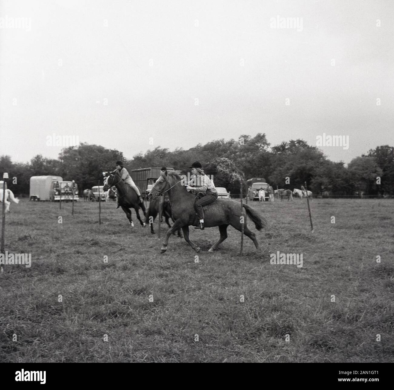 1967, historical, young women competing in a 'gymkhana' in a field at Wendover, Buckinghamshire, England. An equestrian event involving speed racing and timed games for riders on horses, Gymkhanas are often organised by Pony Clubs with the emphasis on young people's participation. Stock Photo