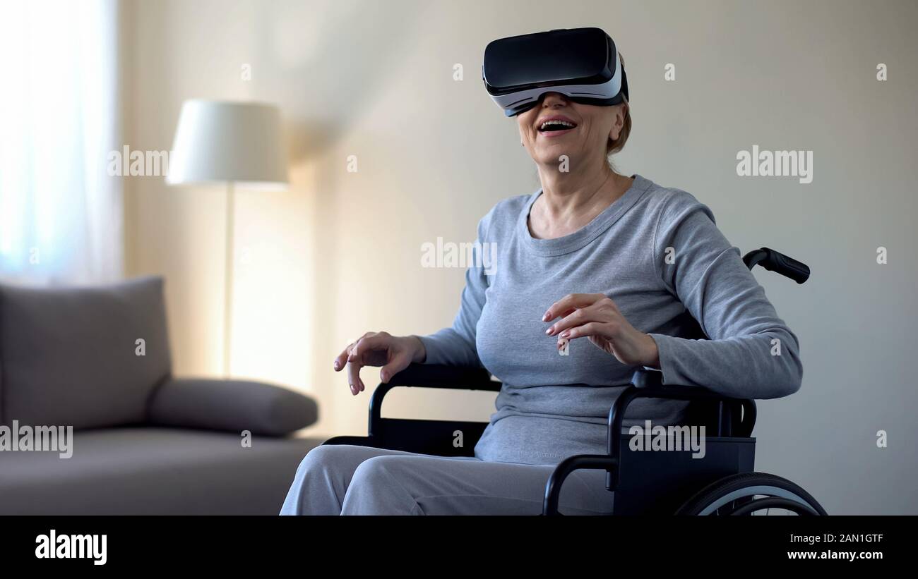 Retired woman in wheelchair wearing vr goggles and enjoying game ...