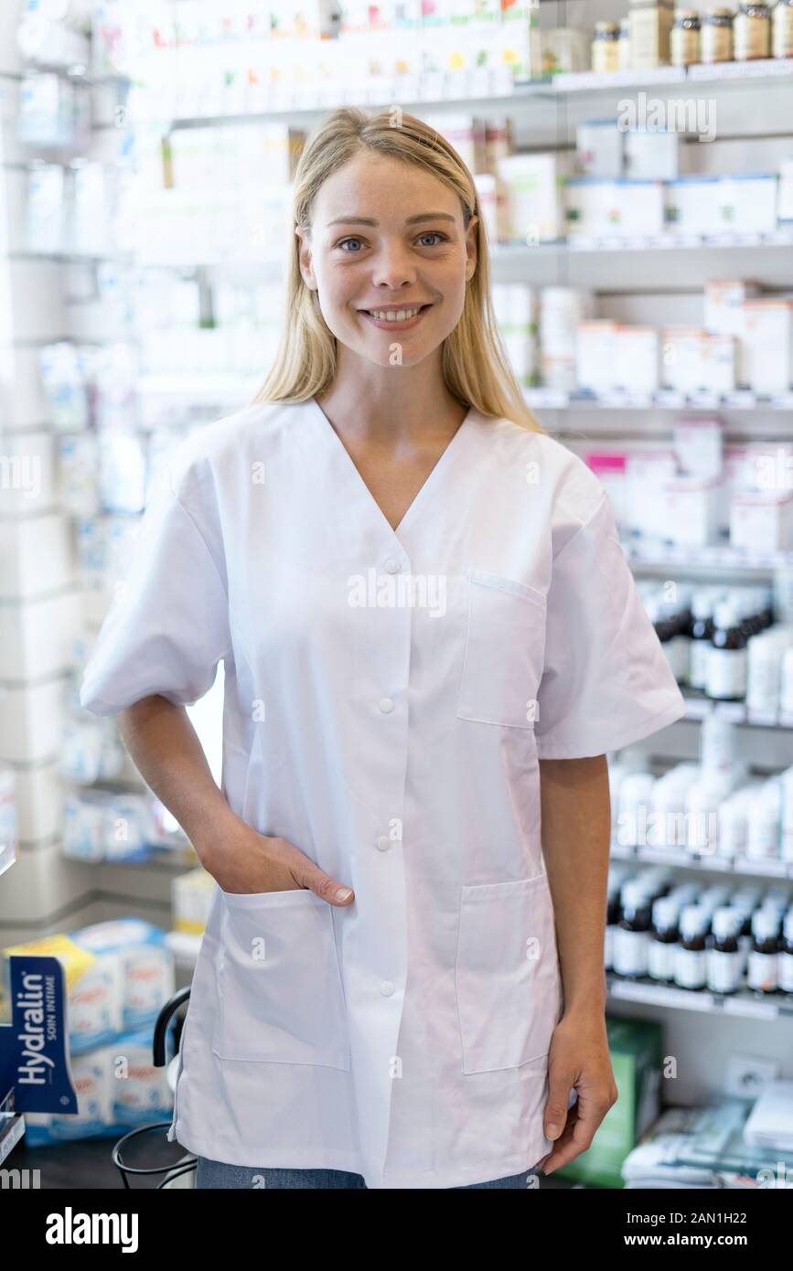Young woman wearing laboratory coat standing in pharmacy Stock Photo