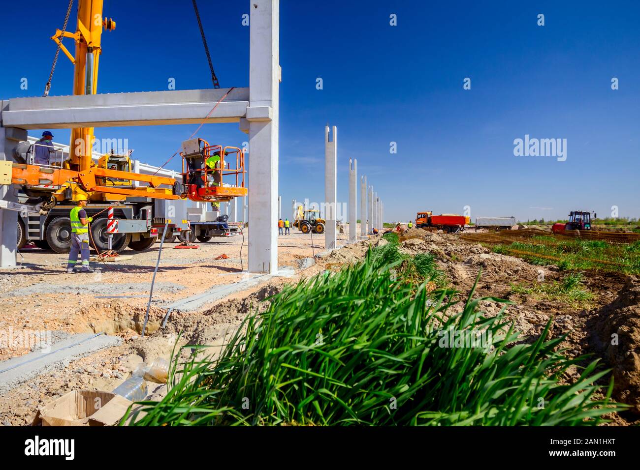 Workers are helping mobile crane to manage concrete joist for assembly ...