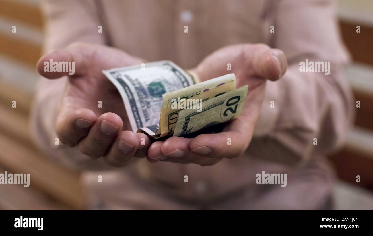 Dollars in old male hands, low living standard, pension poverty, retirement Stock Photo
