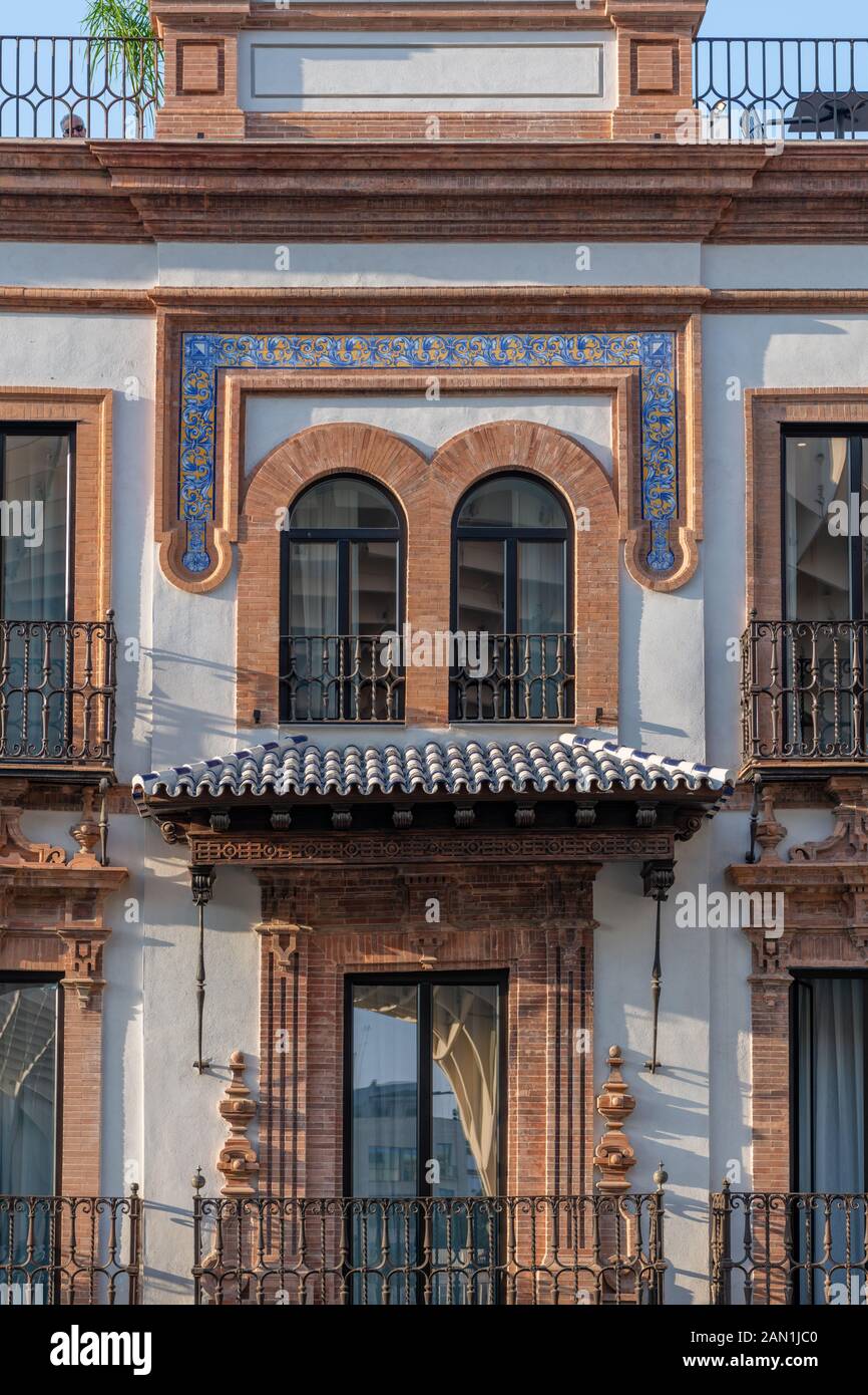 An ornate canopy and tiled border frame windows on the Hotel Casa de Indias in Plaza de la Encarnacion, Seville Stock Photo