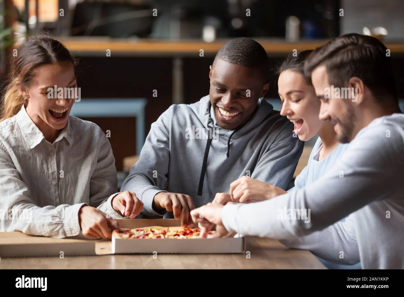 Smiling diverse friends meeting in restaurant enjoy tasty pizza Stock Photo