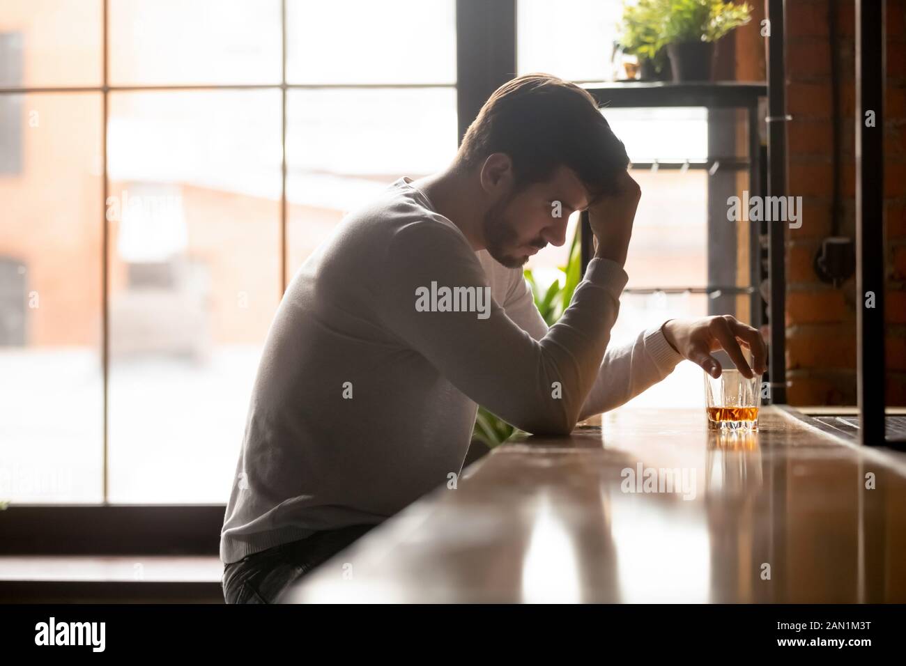 Depressed male drinking alone thinking having life problems Stock Photo