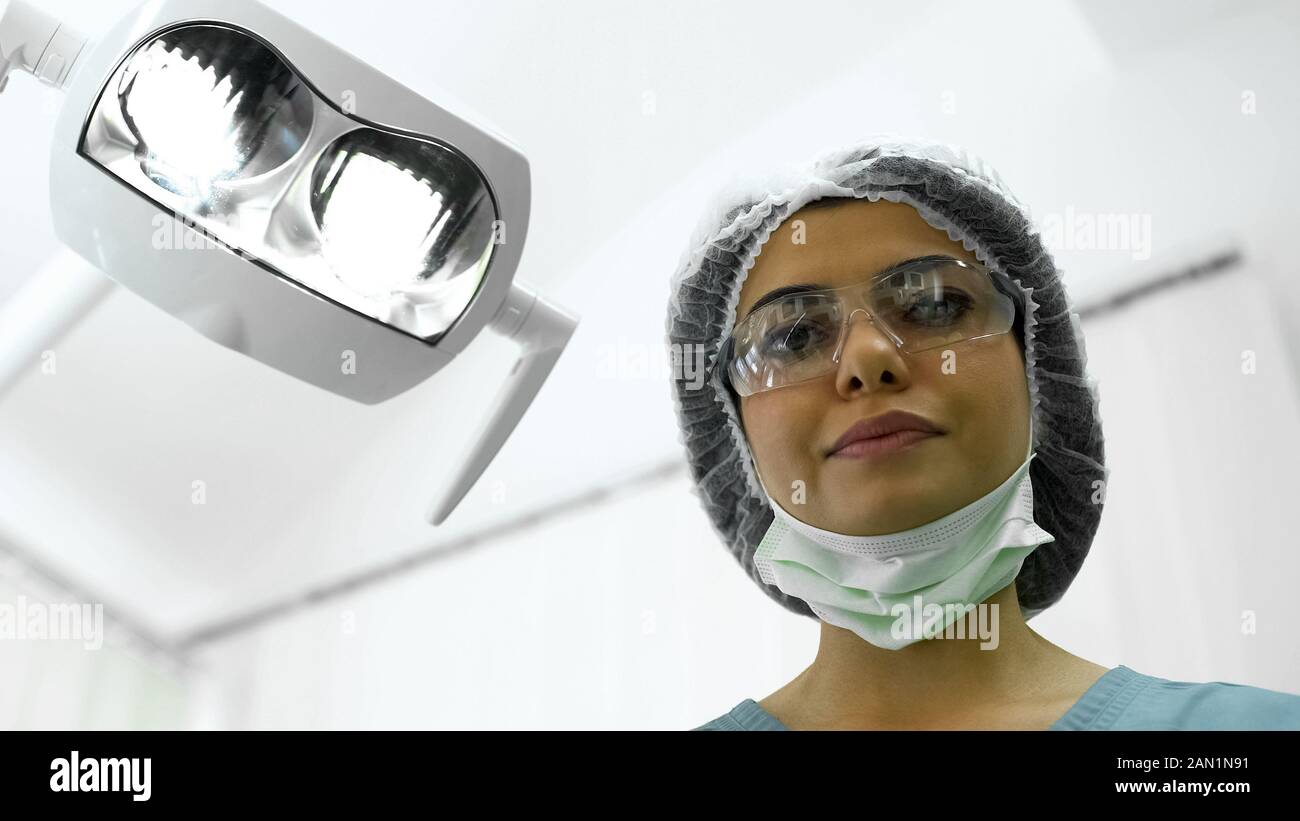 Female nurse adjusting lights before operation, plastic surgery