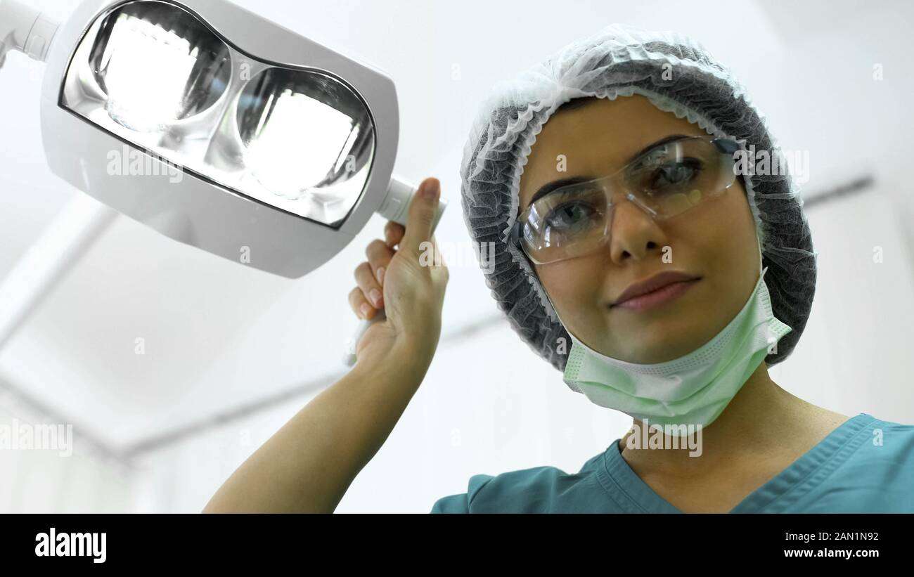 Female plastic surgeon adjusting lights before mole resection, plastic