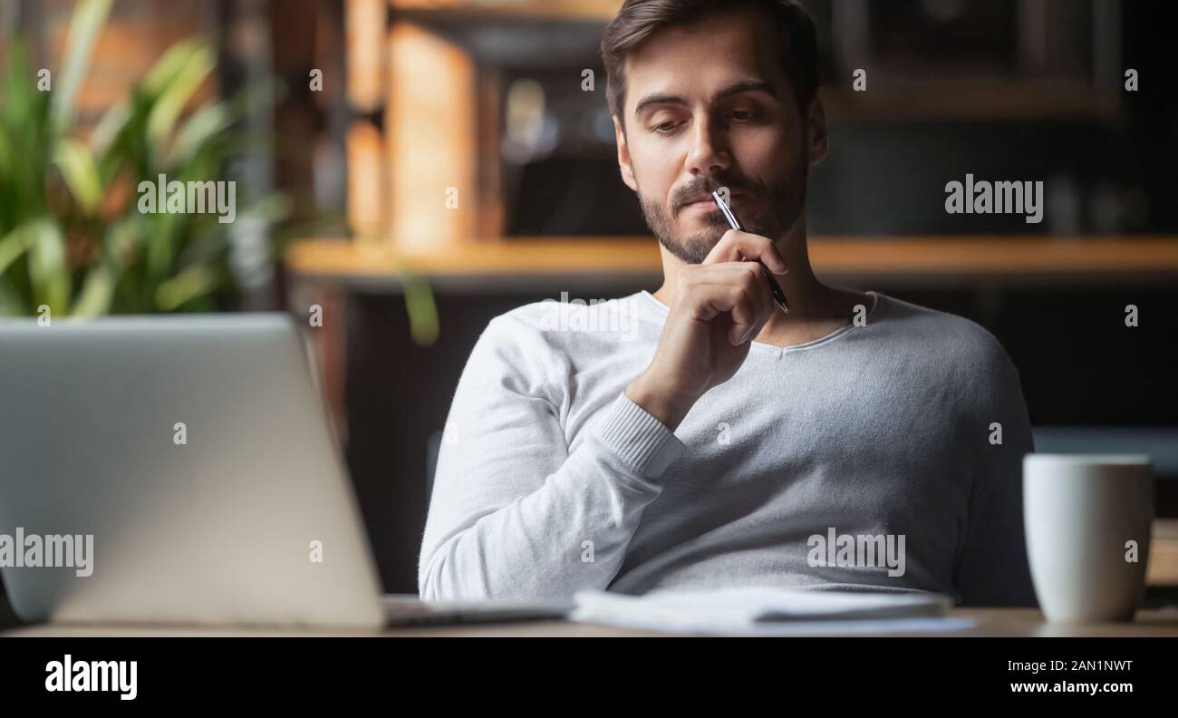 Pensive male thinking over problem solution working on laptop Stock Photo