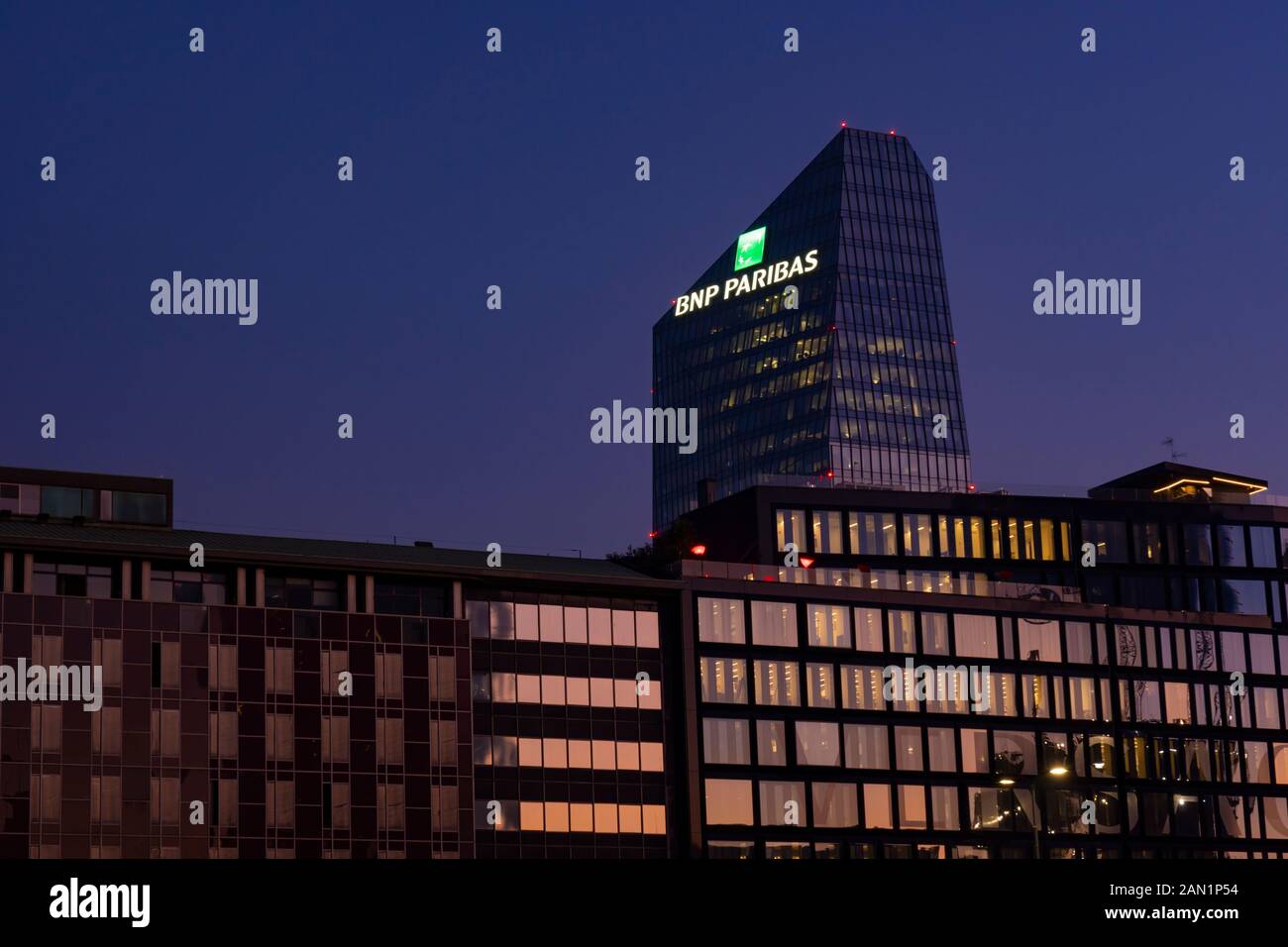 Glass building headquarters of the French bank BNP Paribas with the logo sign illuminated at sunset. Milan, Italy. Stock Photo