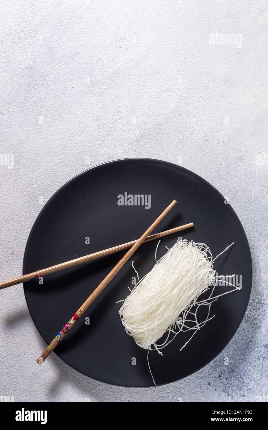 Chinese glass noodles with chopsticks on a dark plate with place for text Stock Photo