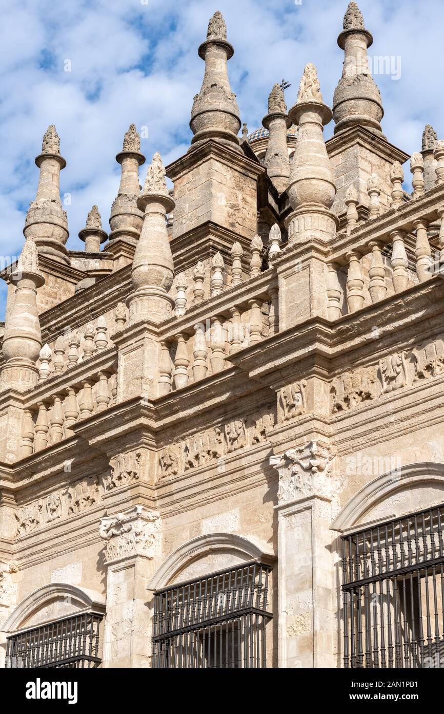 Ornate stone balustrades and pinnacles tower over the façade of the Main Sacristy of Seville Cathedral. Stock Photo