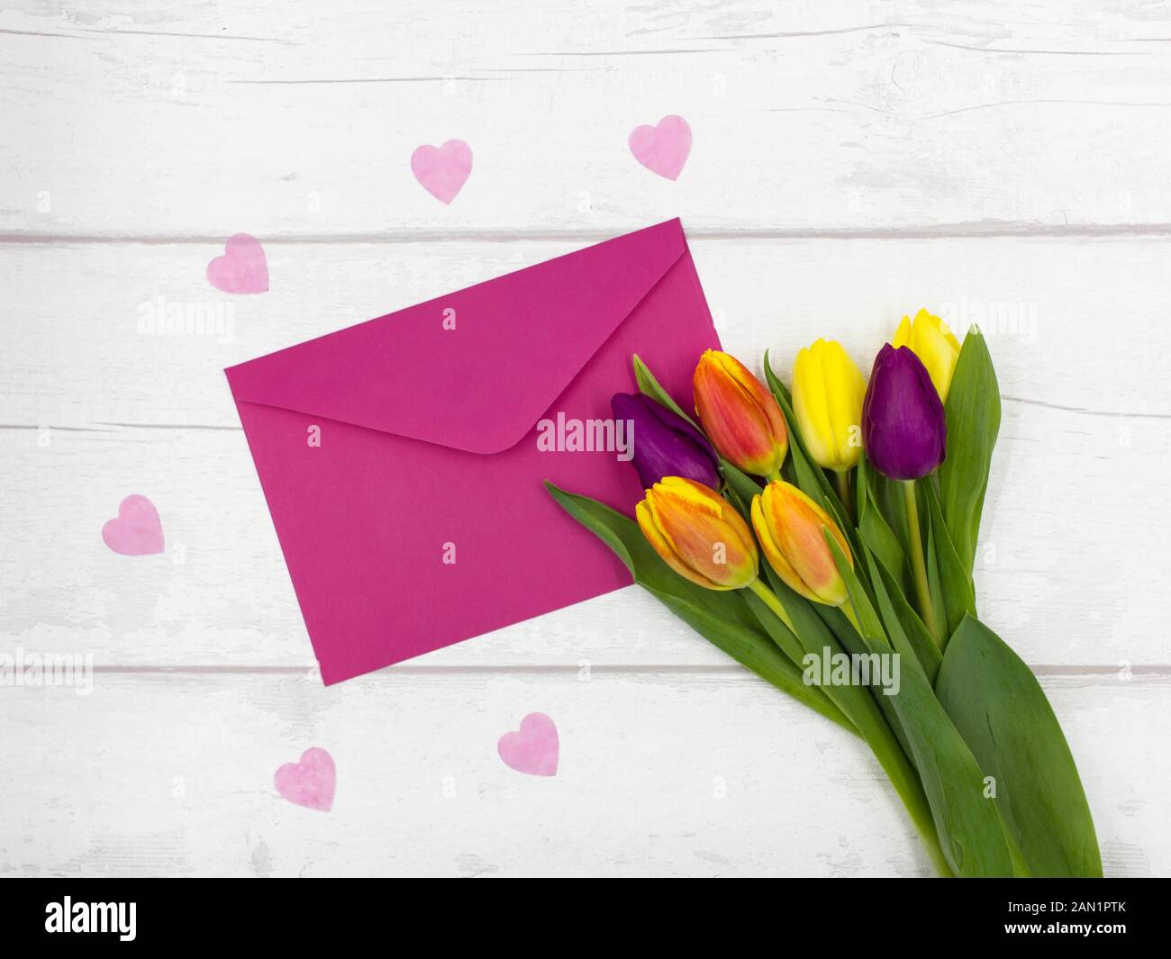 Top View of Beautiful Colourful/Colorful Tulips, with a Pink Envelope and Pink Hearts on A White Rustic Table - Mothers Day/Valentines Stock Photo