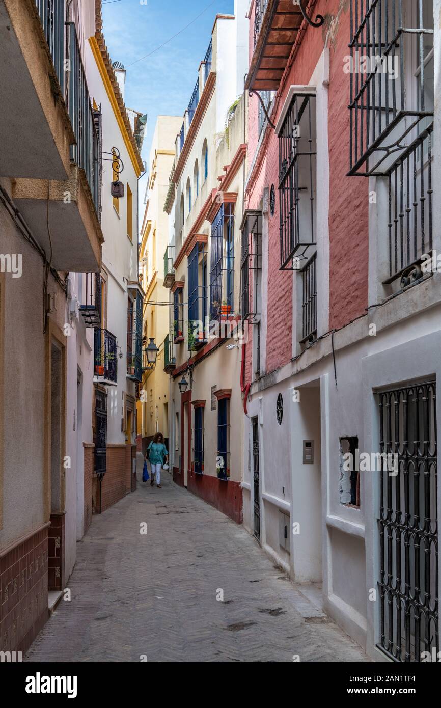 Colourful buildings line a narrow alley in Seville's historic Jewish Quarter. Stock Photo