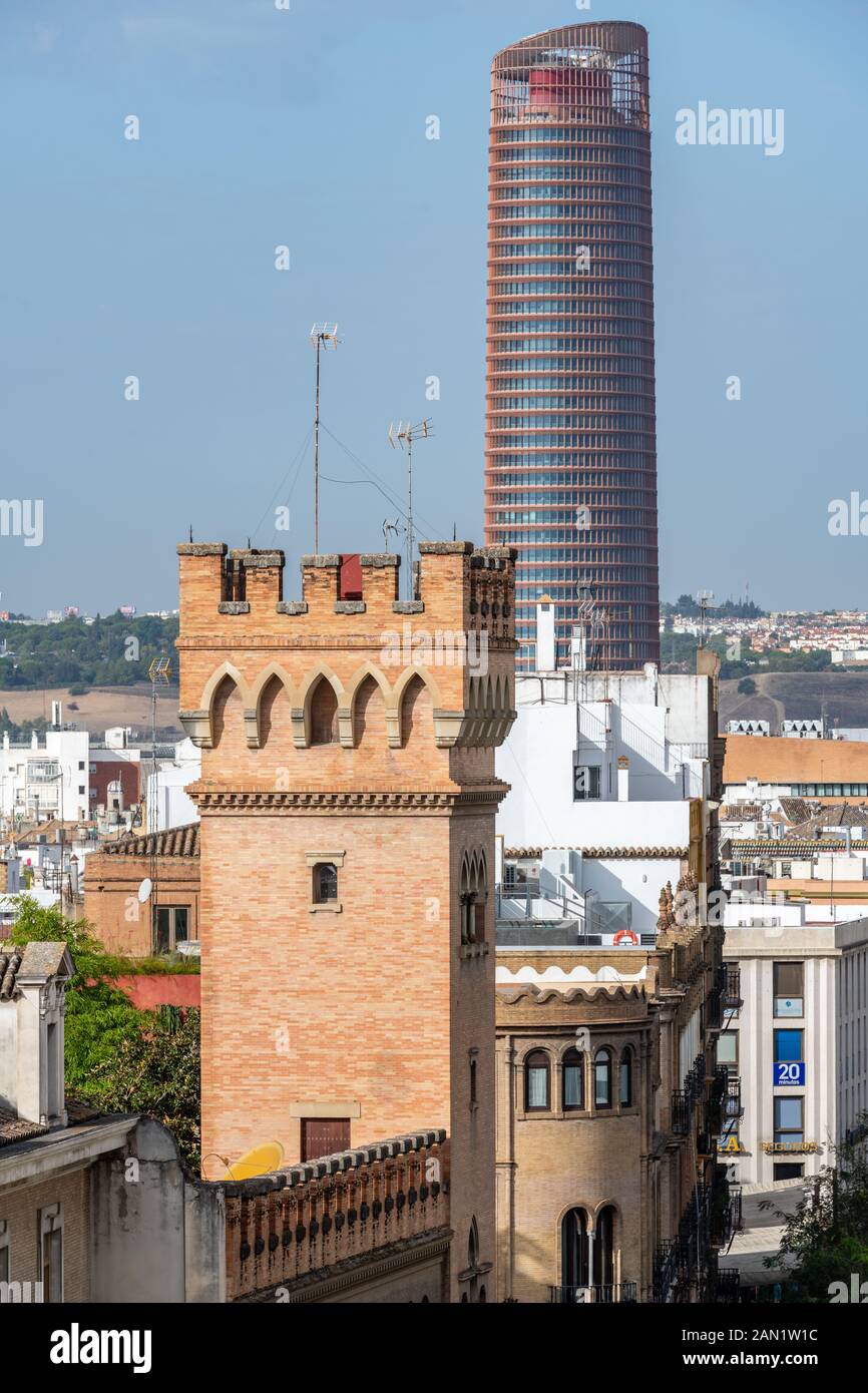 A castellated tower of the 1920s house-palace of the Marquis de la Motilla contrasts with César Pelli's 2015 glass and steel Torre Sevilla. Stock Photo
