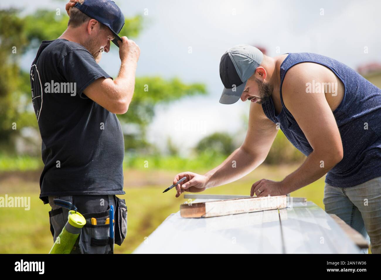Two men measuring brackets for solar panel installation. Stock Photo
