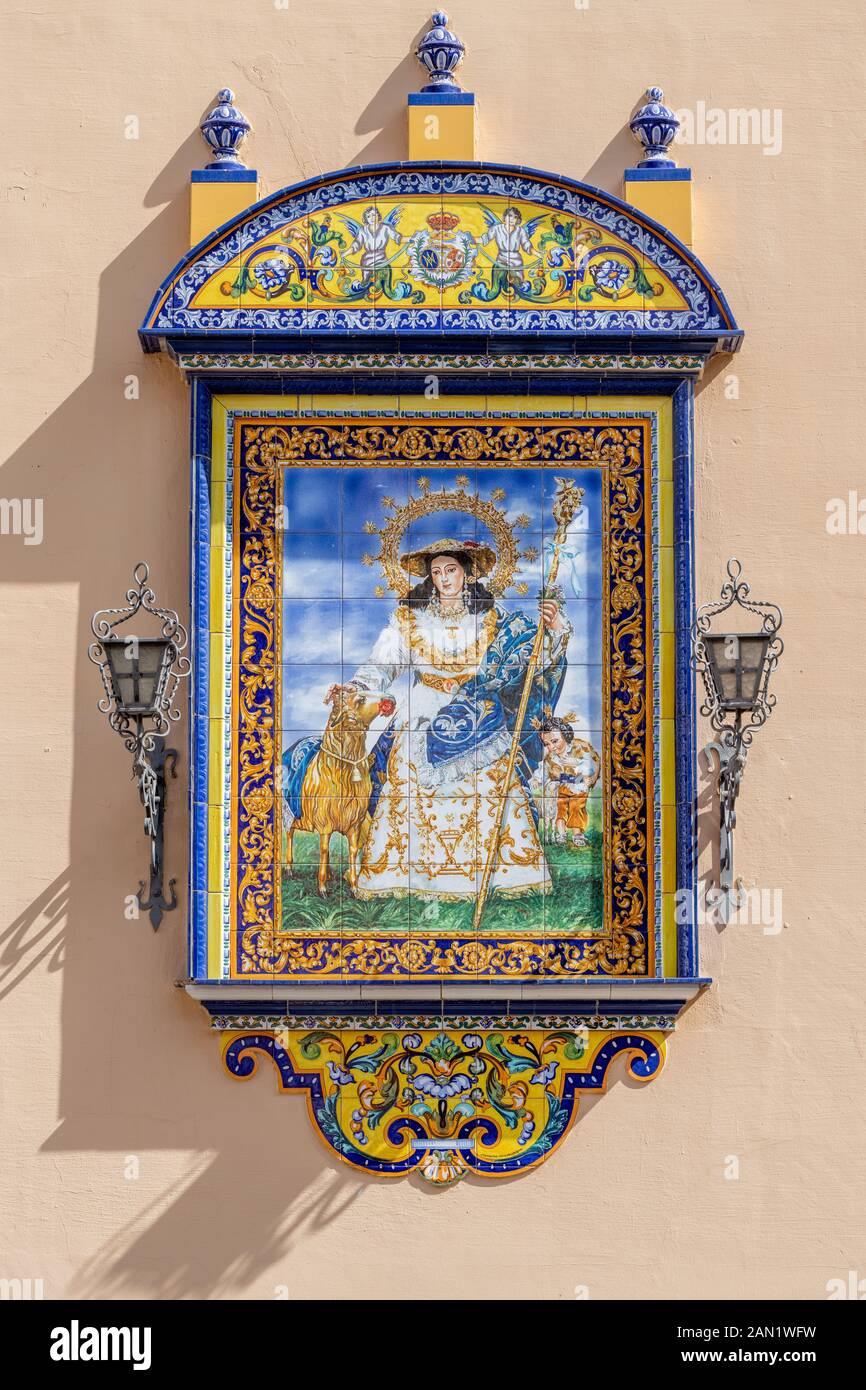 A colourful azulejos plaque of Saint Anne decorates the entrance to the Iglesia de Santa Ana, Seville's oldest parish church, which dates from 1276. Stock Photo