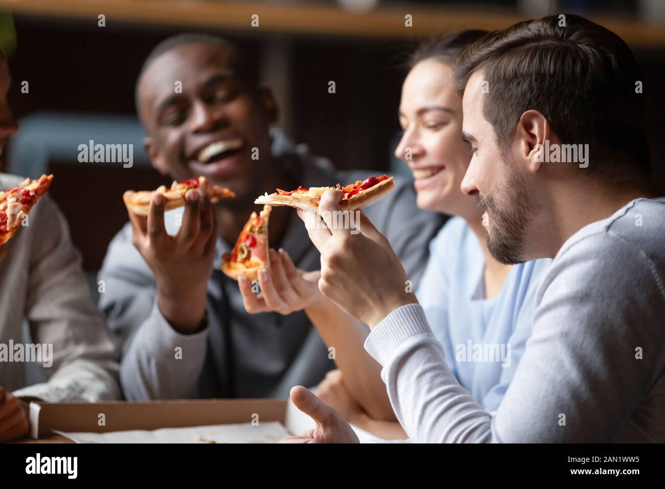 Overjoyed diverse colleagues eating tasty pizza laughing having fun Stock Photo