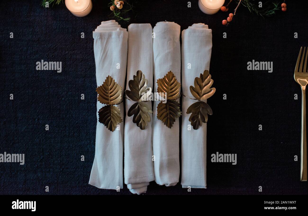 row of gold and white napkins on a decorated dinner table setting Stock Photo