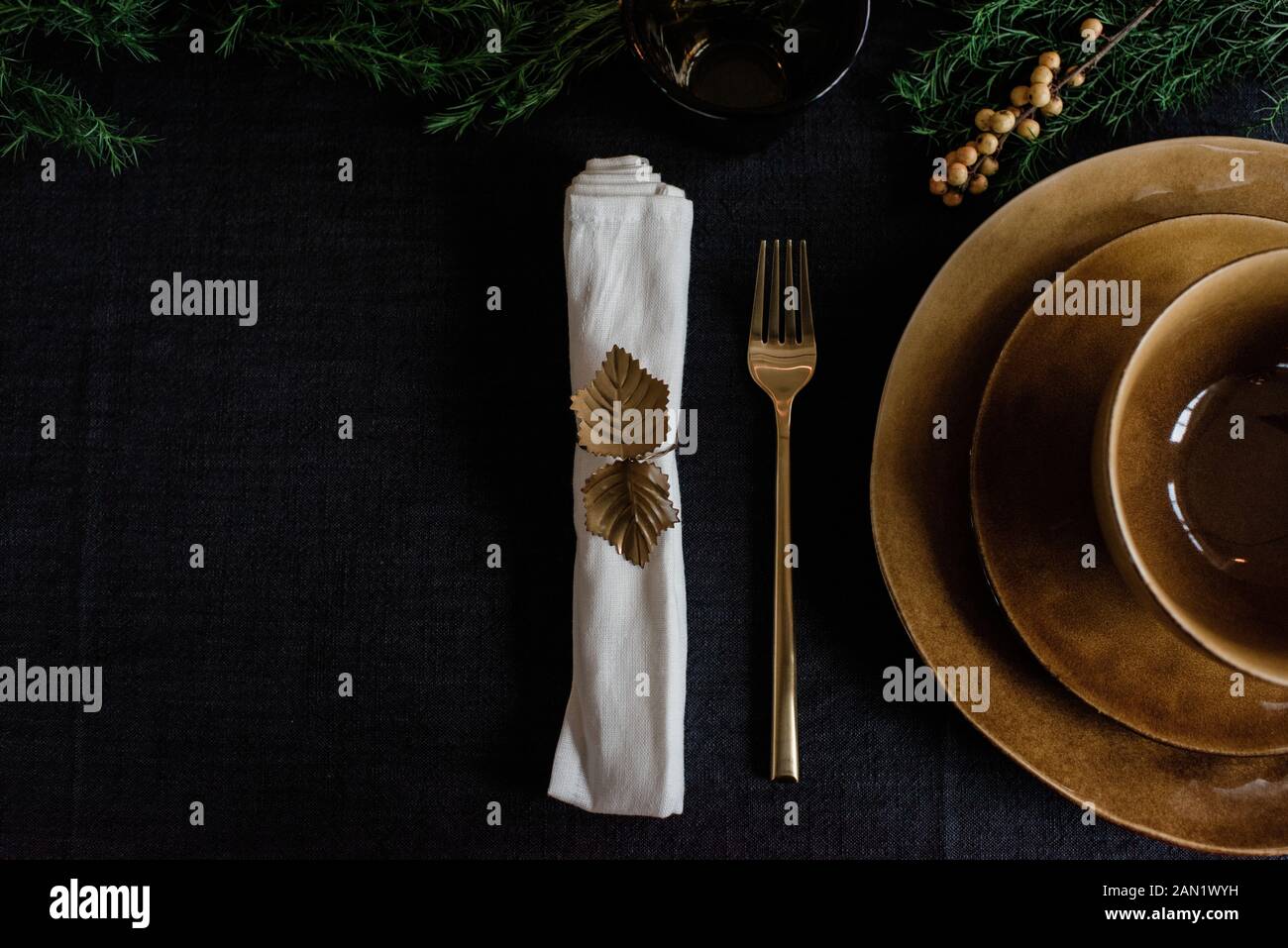 gold napkin holder, plates and fork on a decorated table setting Stock Photo