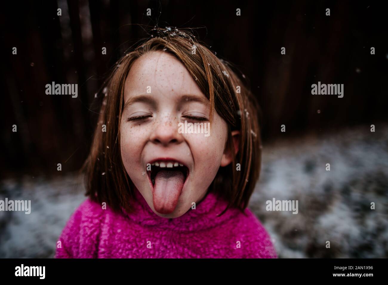 young girl trying to catch snow flakes on her tongue in winter Stock Photo