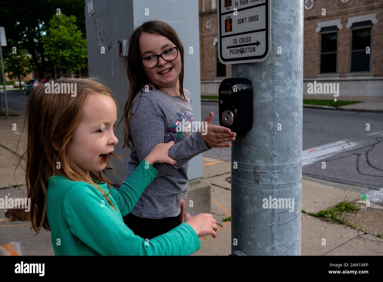 sisters playing with crosswalk button at stop light Stock Photo