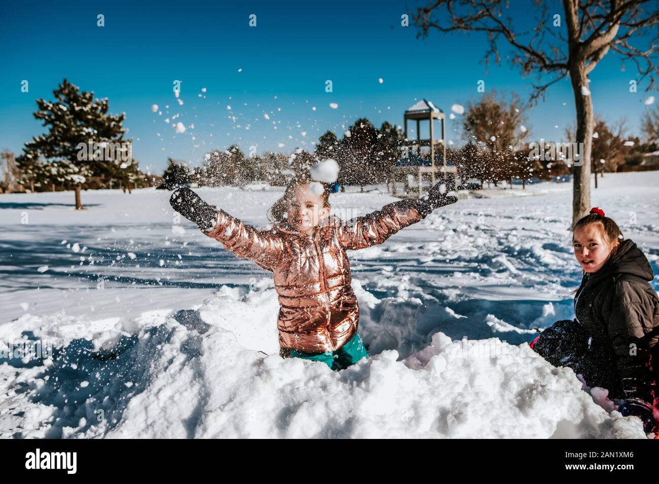 action shot of young girl throwing a snowball during winter Stock Photo