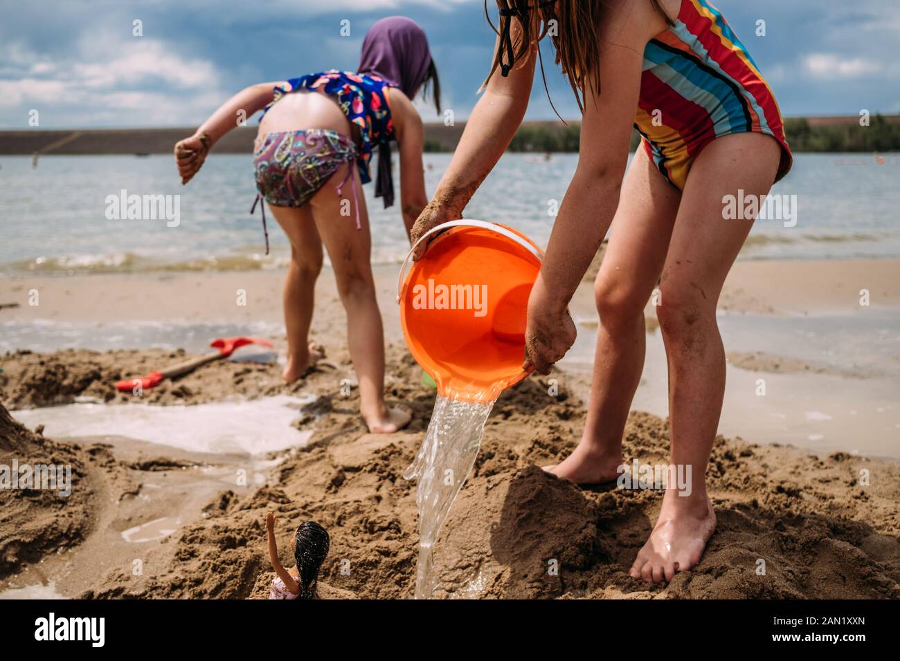 young children playing with water and sand at a lake Stock Photo
