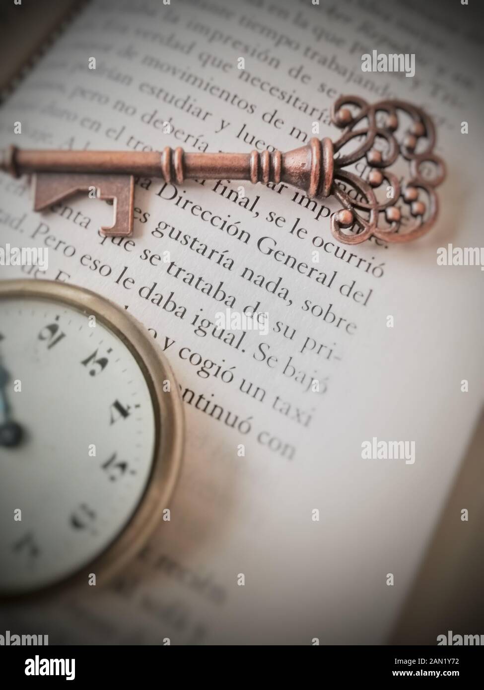 old key detail on book page and pocket watch Stock Photo