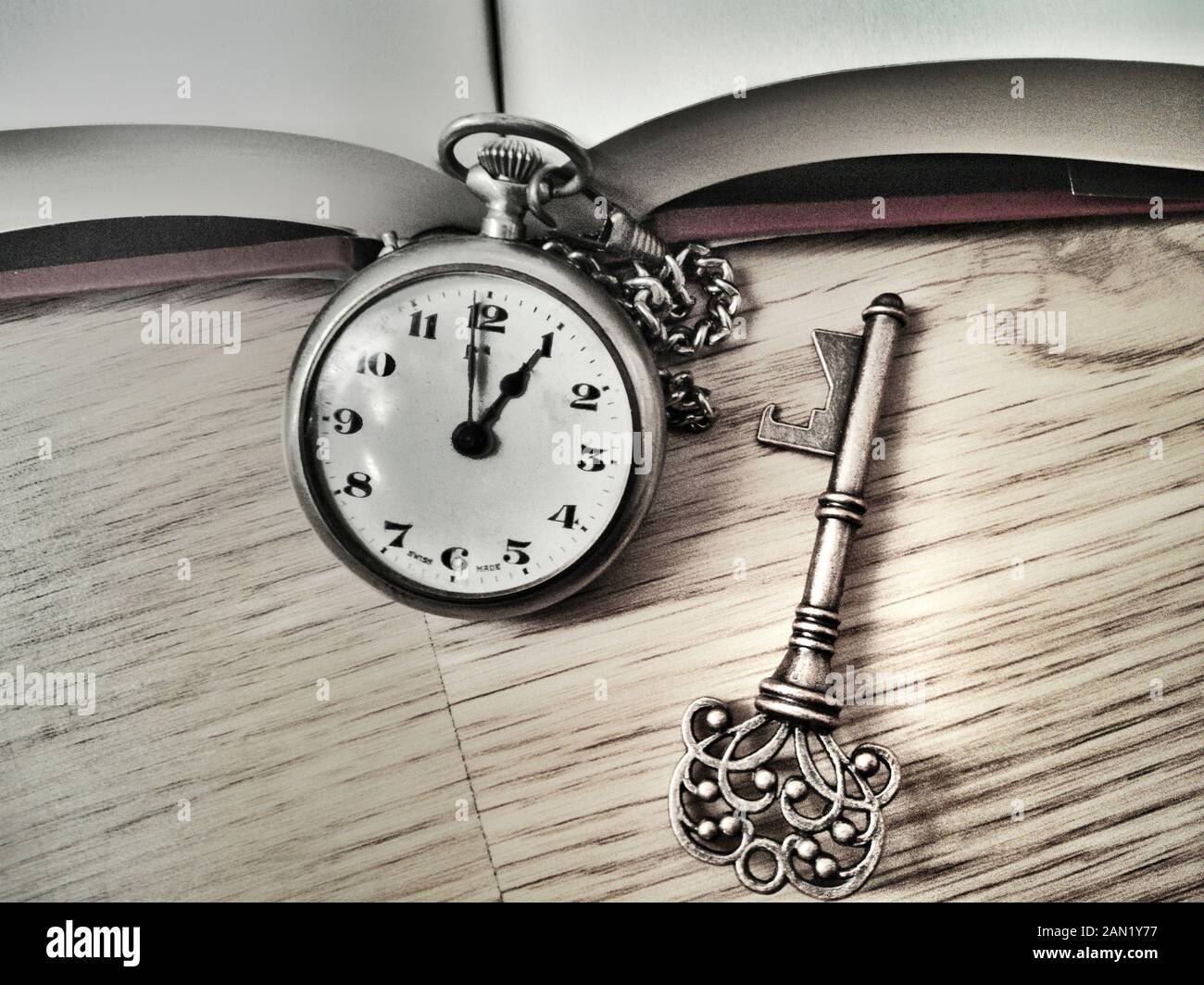 detail of antique pocket watch and key on oak wood floor and textbook Stock Photo