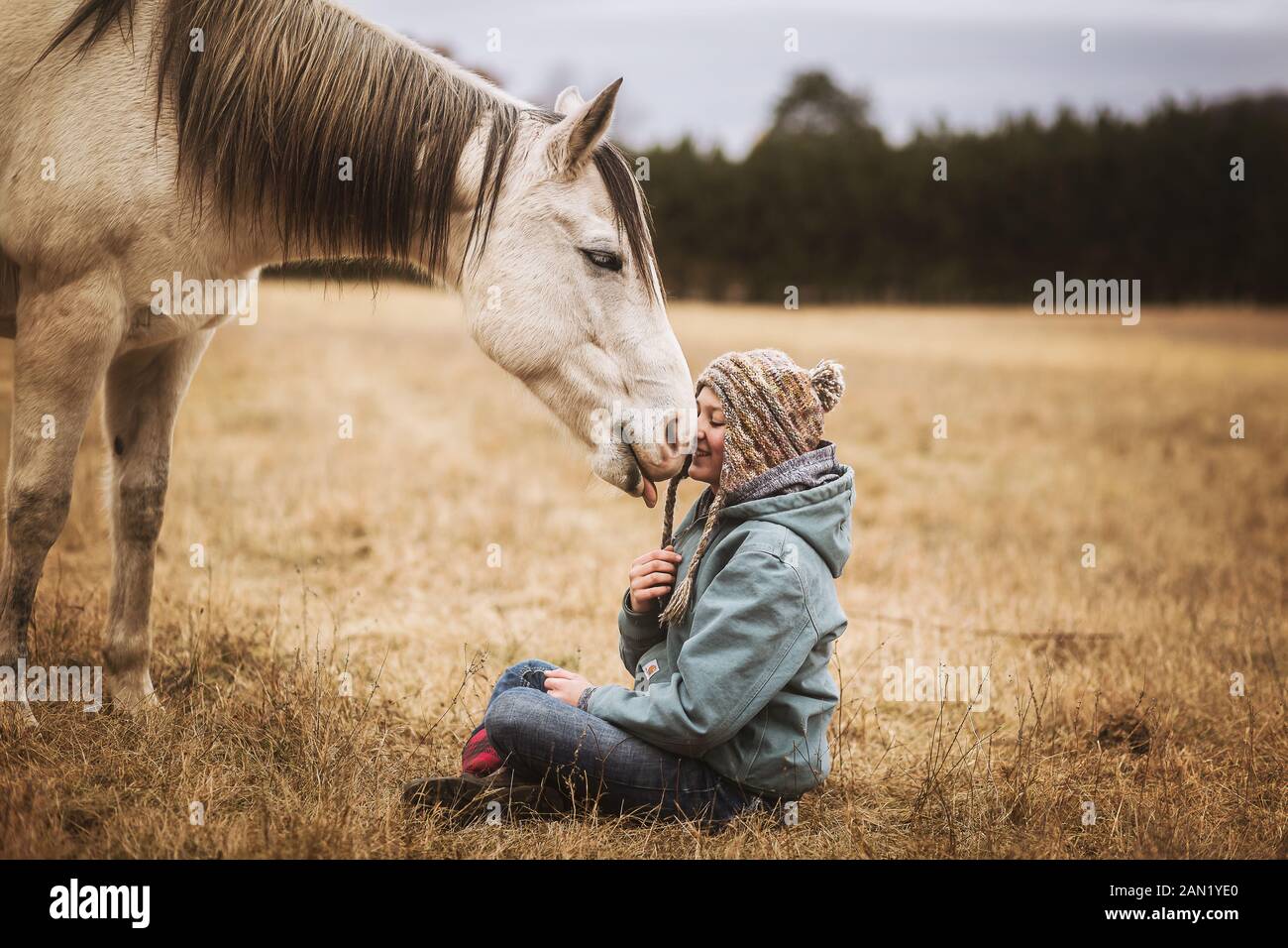 Happy horse licking young girls face in a field in the fall Stock Photo