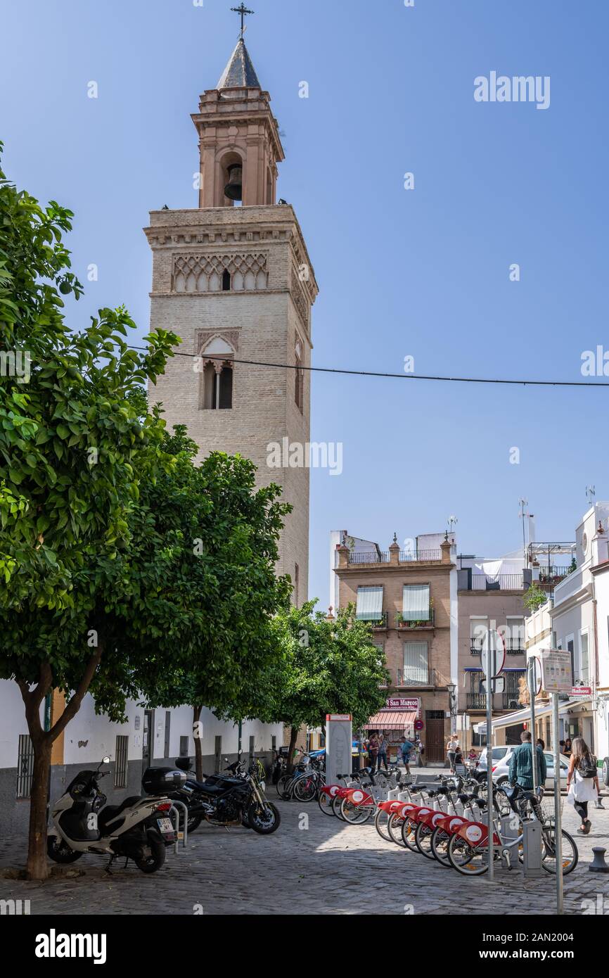 A row of Sevici hire bicycles parked in Calle Vergara in the shadow of Vermondo Resta's 22m tall bell tower for the Iglesia de San Marcos Stock Photo