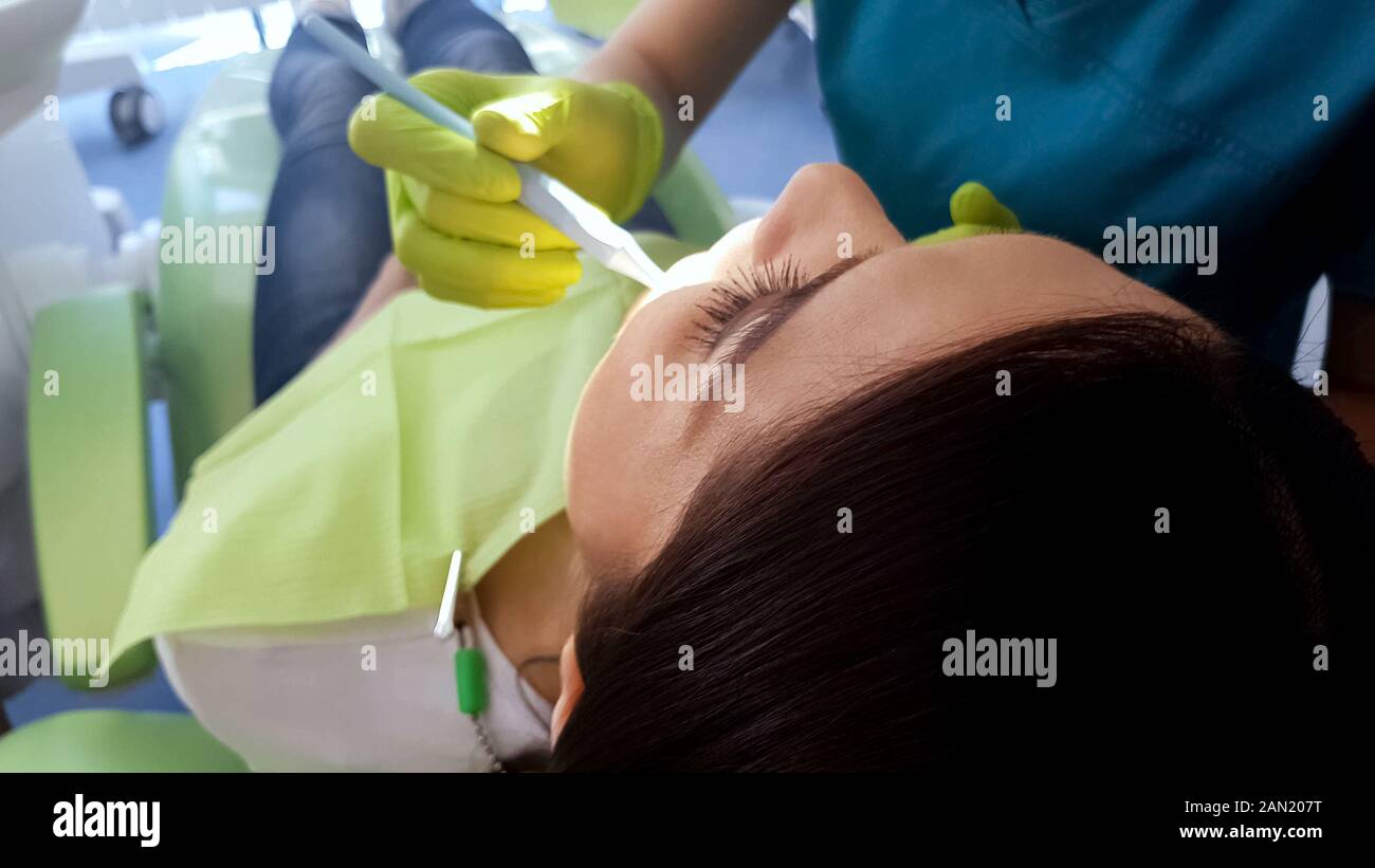 Stomatologist treating female broken tooth, caries removal, sealant