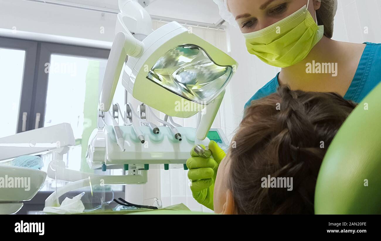 Pediatric dentist preparing to drill patients tooth, caries removal