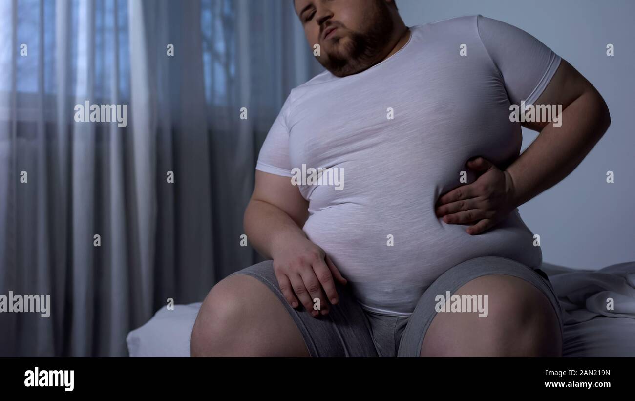 Big young man suffering from stomach pain, acid reflux, fat liver disease, diet Stock Photo