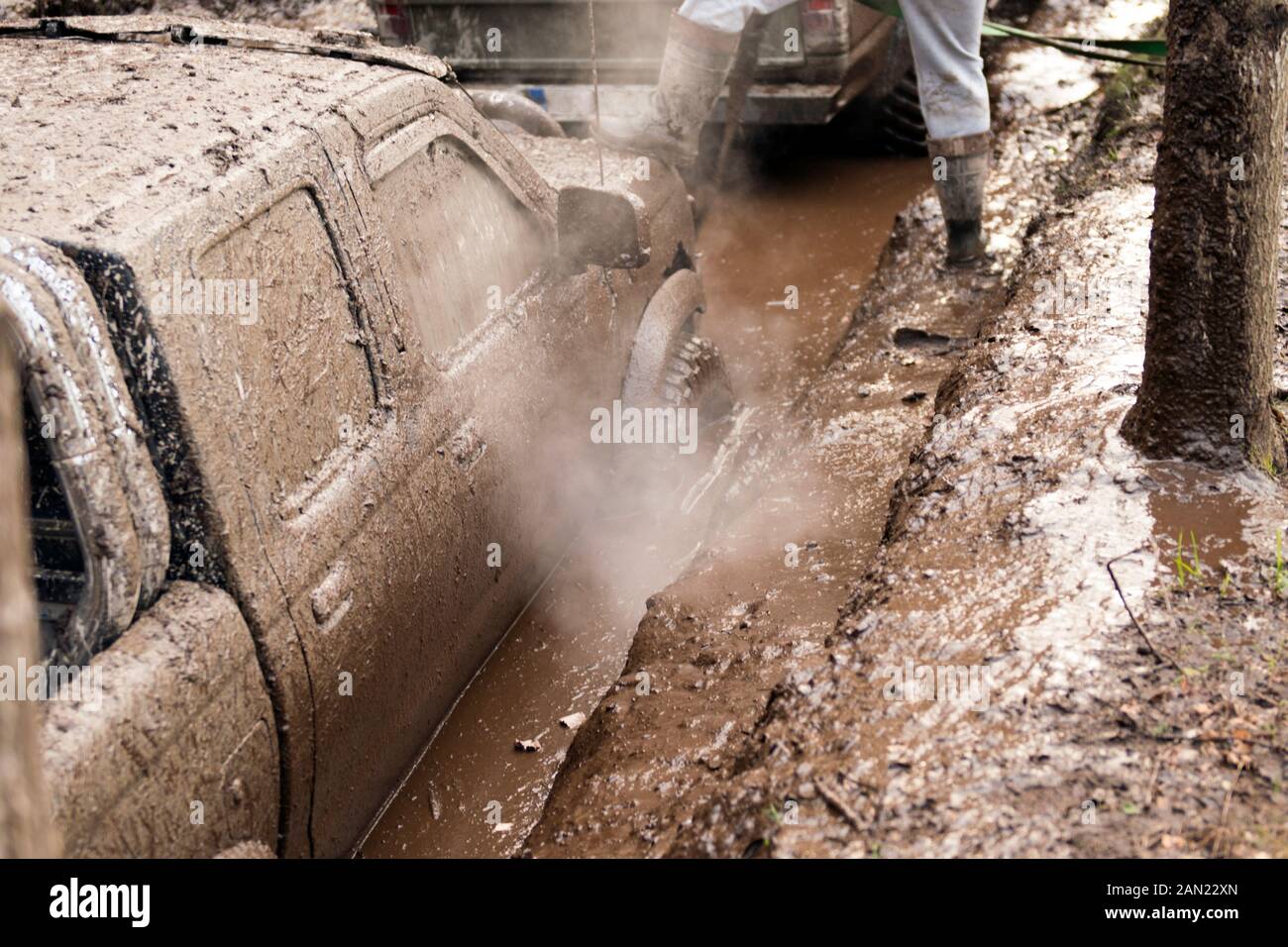 Off-road car going through deep mud holes. Detail of dirty car with filled mud - carwash concept. car wheels. dirty car wheel stands on forest road Stock Photo