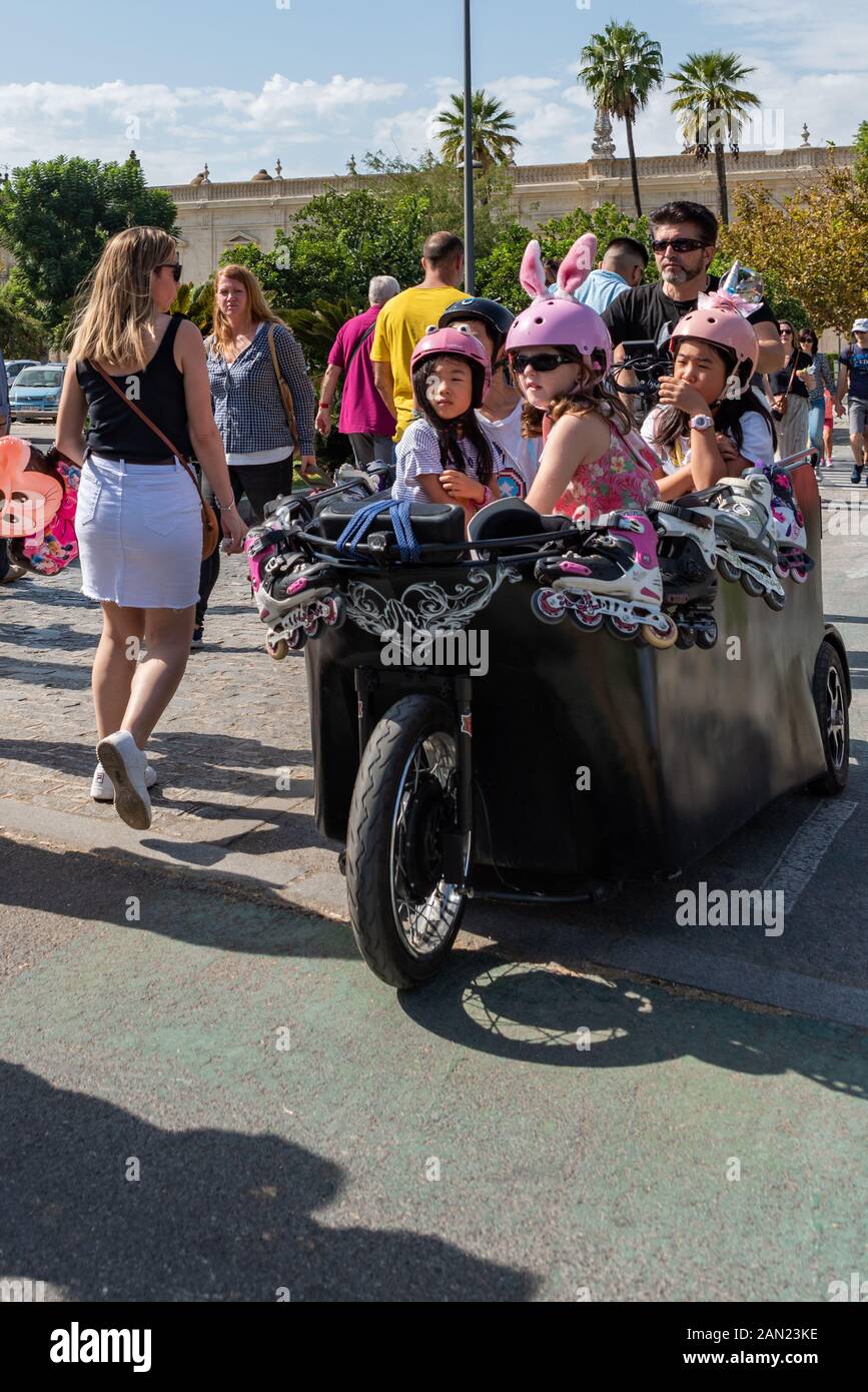 Party girls - young girls in colourful in-line skating gear being taken to their venue in a pedal trike. Stock Photo