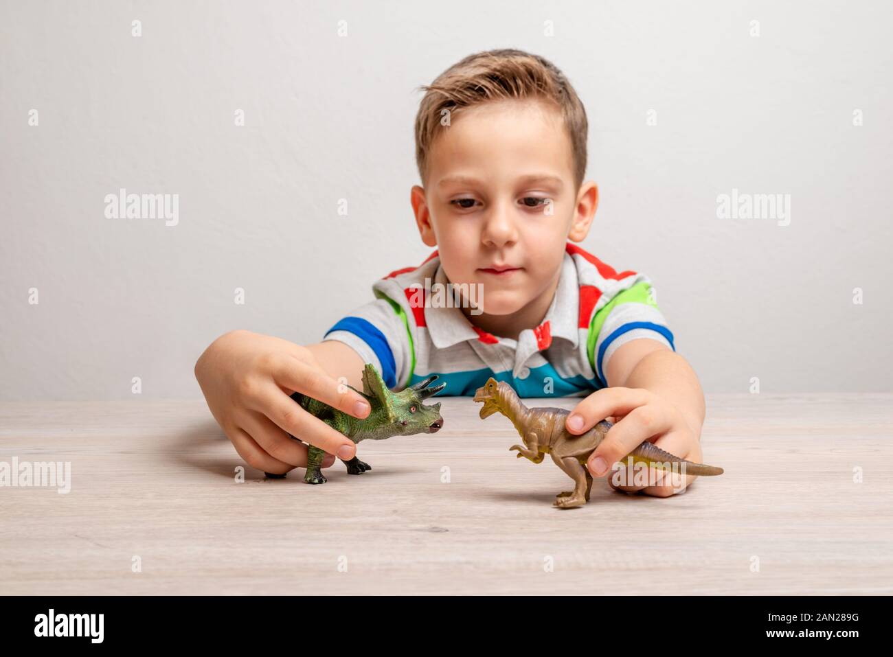 Boy holding dinosaur toys. Concept of developing attention in children through play Stock Photo
