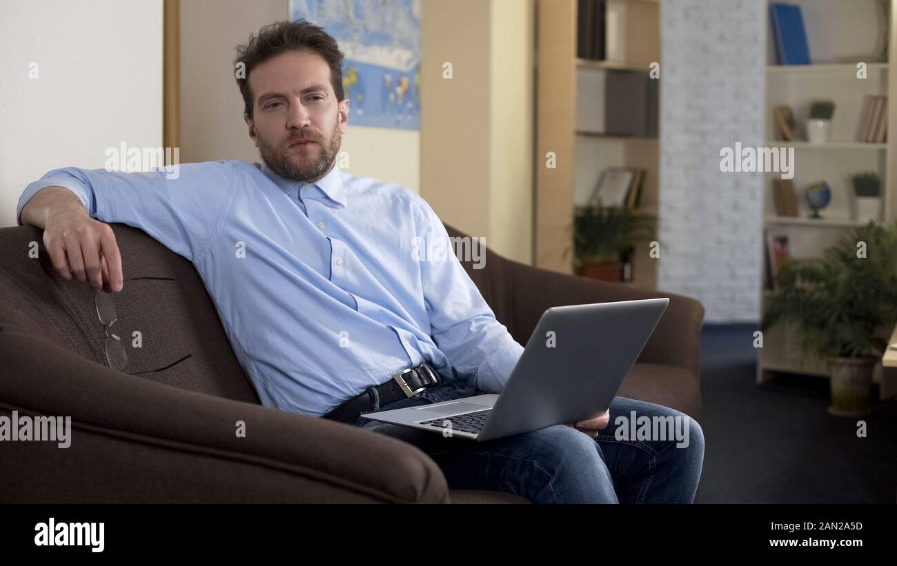 Freelance writer sitting with laptop at home, thinking about work issues Stock Photo