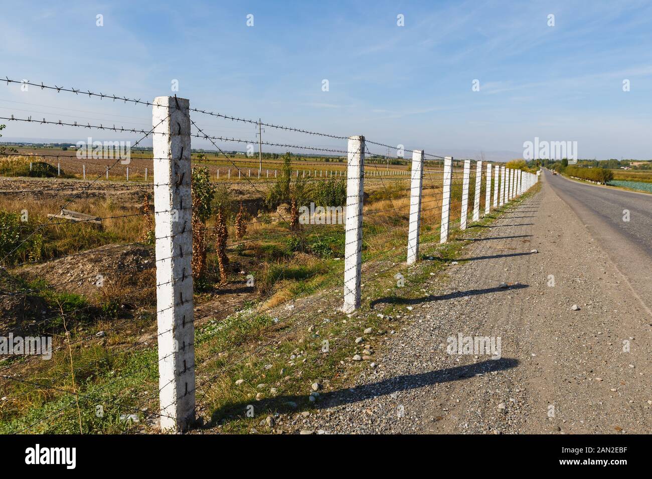 barbed wire fence along the road, state border between Kyrgyzstan and Uzbekistan Stock Photo